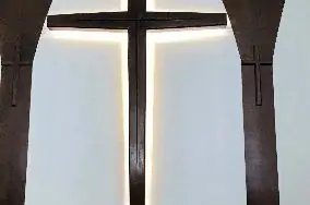 Church interior with a timber cross lit from behind by concealed accent lighting