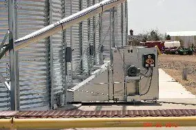 Grain handling equipment with an electrical control box beside a steel silo