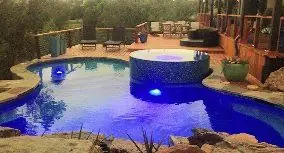 Backyard pool at dusk with underwater and landscape lighting switched on